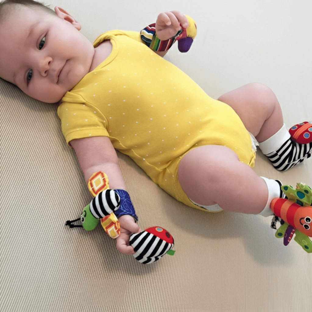 Hochet Bébé Rigolo Set 4 Pièces - Sensoriel Complet Bébé en body jaune avec hochets sensoriels