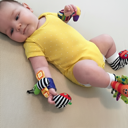 Bébé en body jaune avec hochets sensoriels