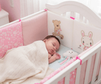 Contour de Lit Bébé qui dort avec couverture et hochet dans le lit avec contour rose