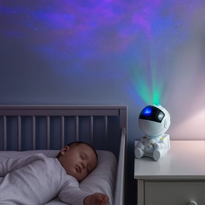 projecteur veilleuse cosmonautes sur table avec bébé qui dort
