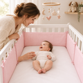 Tour de lit rose avec bébé éveillé et maman dans une chambre cosy