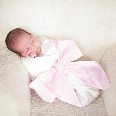 une couverture pour emmaillotage rose bébé qui dort